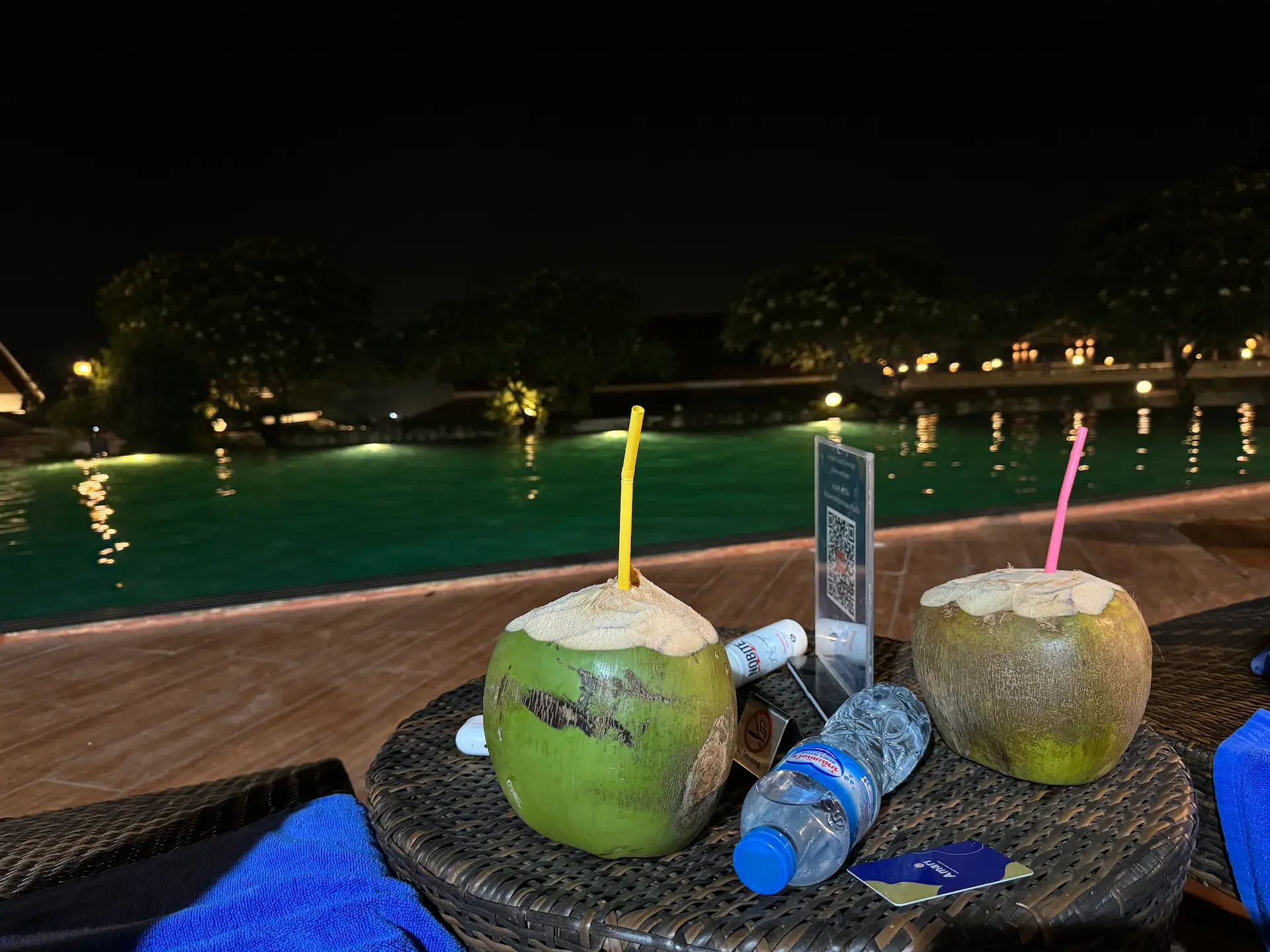 Green coconuts and drinks at night by an illuminated pool, Hội An