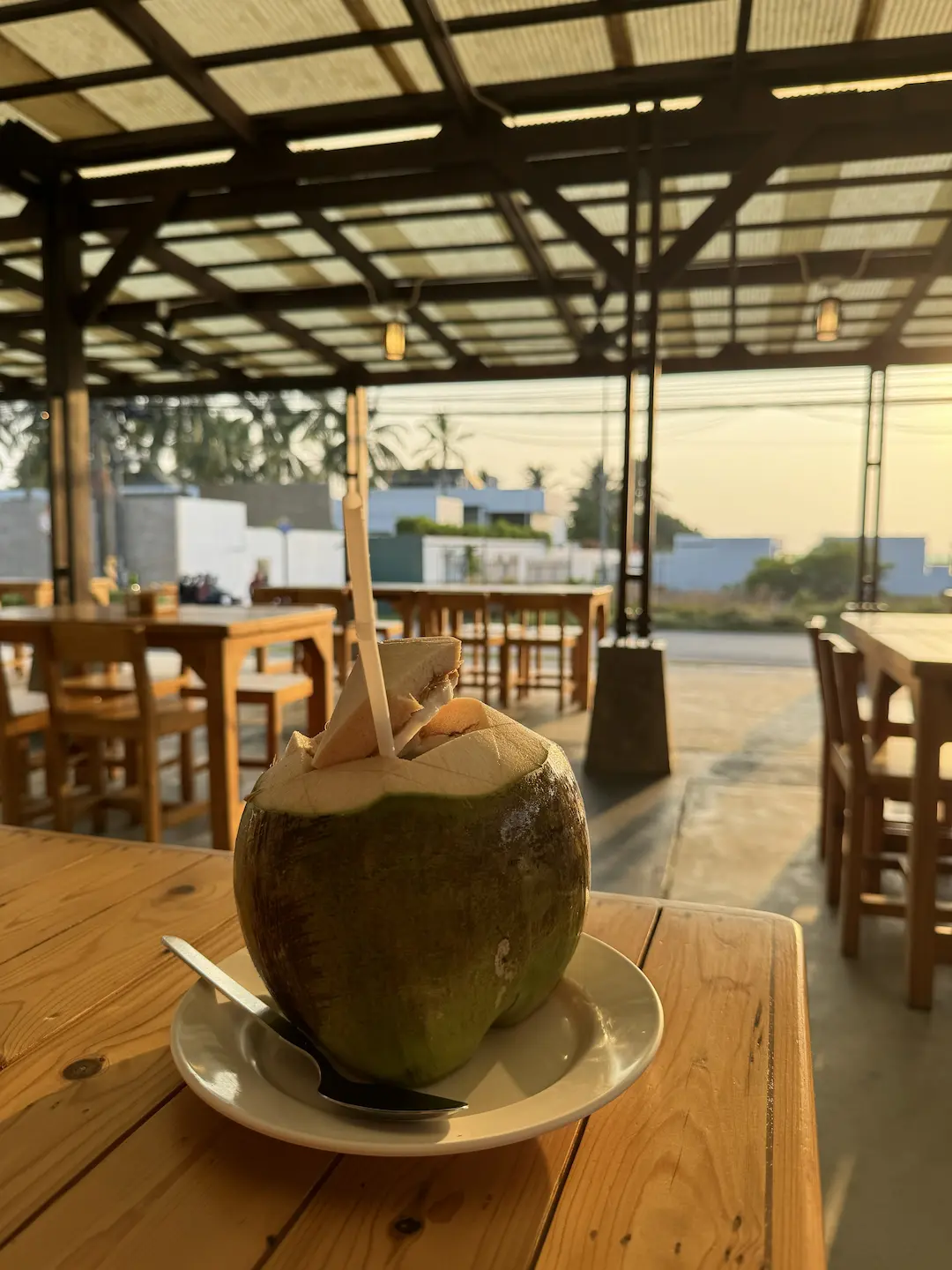 Coconut on white plate at an open-air restaurant with sea view in background